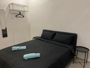 ein schwarzes Bett mit zwei blauen Kissen darauf in der Unterkunft Dudu Guesthouse Ipoh in Ipoh