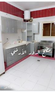 a kitchen with gray cabinets and a red wall at فله فاخرة in Tanomah