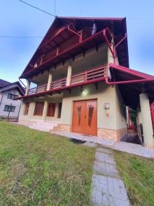 une maison avec des portes rouges et une cour herbeuse dans l'établissement Pensiunea Geta, à Rucăr