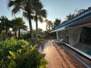 une maison avec une terrasse plantée de palmiers en arrière-plan dans l'établissement Costabella / Marbella a mar, à Marbella