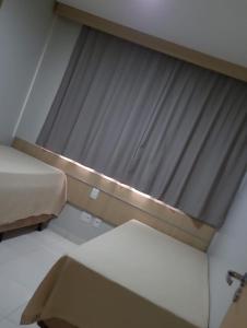 a room with a bed and a large window at Apartamento da Gigi Caldas in Caldas Novas