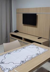 a living room with a tv and a table with a bed at Apartamento da Gigi Caldas in Caldas Novas