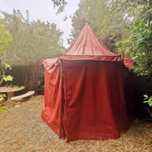 uma tenda vermelha no meio de um jardim em Le Camp du Chevalier em Valençay