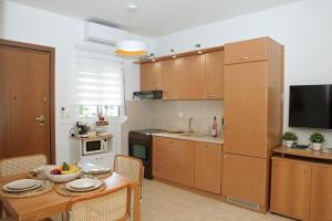 a kitchen with wooden cabinets and a table and a television at Myrto's luxury house in Kallithea Halkidikis