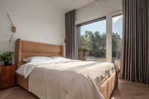um quarto com uma cama e uma grande janela em Pušų Terasos-21 em Klaipėda