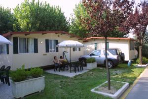 a woman sitting at a table in front of a house at Camping Wien in Peschiera del Garda