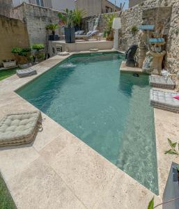 a swimming pool in a yard with a stone wall at Le Baratier - Demeure de charme Sauna & Piscine in Calvisson