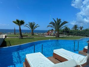 a large swimming pool with palm trees and the ocean at Sea Coast Resort Halkidiki in Yerakiní
