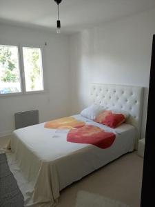 um quarto com uma grande cama branca e 2 almofadas em Maison au coeur des vignes em Cussac-Fort-Medoc