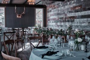 una sala da pranzo con tavoli, sedie e un muro di mattoni di Creekside Villa a Canmore