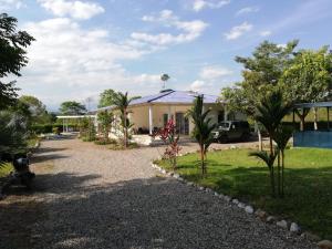 a house with trees and a gravel driveway at Casa Campestre con Piscina Jacuzzi y Golfito in Villavicencio