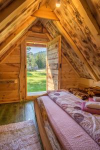 sypialnia w drewnianym domku z dużym oknem w obiekcie Eco Camp Chalets pod Gorom w mieście Žabljak