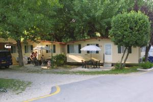 a house with tables and umbrellas in front of it at Camping Wien in Peschiera del Garda