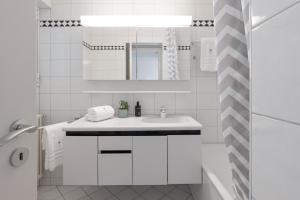 un bagno bianco con lavandino e specchio di VIEW Appartement including Parking ad Ascona