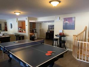 a ping pong table in the middle of a living room at Dragonfly Inn Loft & Walkout Suites in Sherwood Park