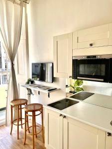 a kitchen with white cabinets and bar stools at Belgrave Studio Apartments, Westminster London in London