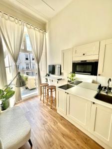 a kitchen with white cabinets and a large window at Belgrave Studio Apartments, Westminster London in London