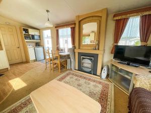 uma sala de estar com televisão e lareira em Brilliant Caravan With Decking And Wifi At Dovercourt Park In Essex Ref 44010a em Great Oakley