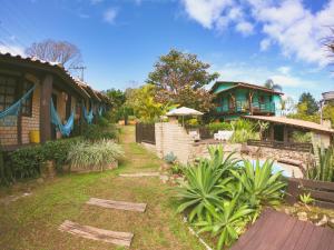 ein Haus mit einem Hof mit Pflanzen und einem Gebäude in der Unterkunft Haleakala Hostel & Pousada in Praia do Rosa
