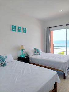 two beds in a bedroom with a view of the ocean at KaiBlue Hotel y Restaurante in La Libertad