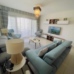 uma sala de estar com um sofá azul e uma televisão em شالية بمراسي فرش فندقي السعر شامل الكروت em El Alamein