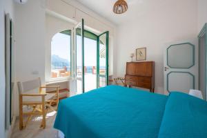 a bedroom with a blue bed and a table and chair at Villa Cavalluccio Marino in Minori