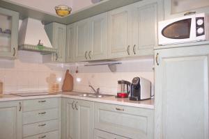 cocina con armarios blancos y microondas en A Casa di Ale en Sorso