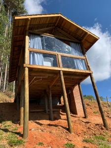 a wooden building with glass windows on a dirt field at Montanha Home in Monte Verde