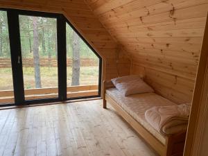 a log cabin with a bed in a room with windows at Dom Stodoła Borsk in Borsk
