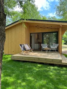 a cabin with a deck with two chairs and a table at Camping Swory in Swornegacie 