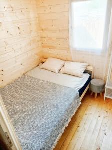 Łóżko w drewnianym pokoju z oknem w obiekcie Dreamholia w Jastarni