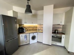 een keuken met witte kasten en een wasmachine en droger bij Cabacum Beach Residence AP.20 in Varna