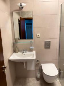 een badkamer met een wastafel, een toilet en een spiegel bij Cabacum Beach Residence AP.20 in Varna