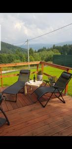 2 sillas y una mesa en una terraza de madera en Domek na Folwarku, en Tarnawa Dolna