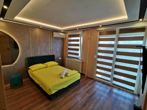 a bedroom with a bed with yellow sheets and wooden floors at Princ Lux Spa with free parking in Novi Sad