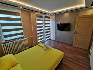 a room with a yellow bed and a television at Princ Lux jaccuzi and sauna with free parking in Novi Sad