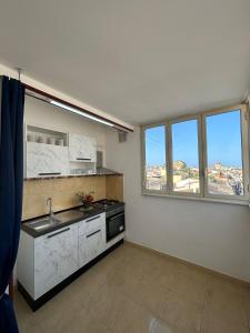 a kitchen with a sink and a stove and windows at Le Trottole Apartment in Palermo