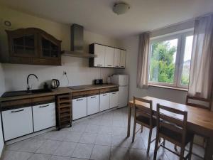 a kitchen with white cabinets and a table and chairs at Na Dębowej- Apartament/dom 2 pokoje-prywatny las in Szczytna