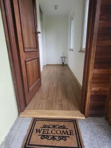 un pasillo con una alfombra de bienvenida frente a una puerta en Na Dębowej- Apartament/dom 2 pokoje-prywatny las, en Szczytna