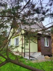 una pequeña casa amarilla con escaleras delante en Na Dębowej- Apartament/dom 2 pokoje-prywatny las, en Szczytna