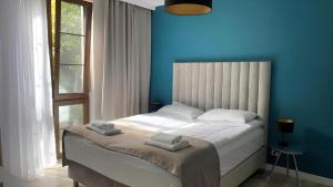 a blue bedroom with a bed with towels on it at Sopot Marina Beach Suites in Sopot
