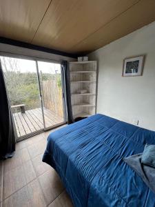 1 dormitorio con cama azul y balcón en Casa CALMA en Villa Serrana, en Villa Serrana