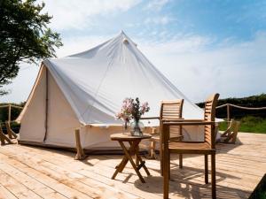 a tent with two chairs and a table in front of it at Hafod Hir in Cross Inn