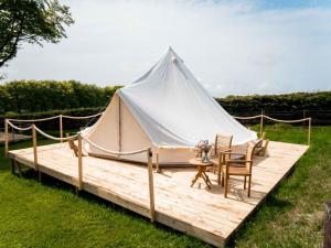 Tenda bianca con tavolo e sedie su una terrazza in legno di Hafod Hir a Cross Inn