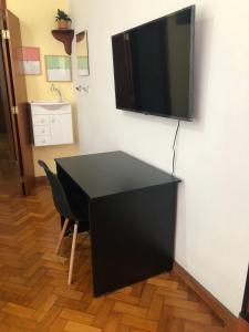 a black desk with a flat screen tv on a wall at Loft no CENTRO DO RIO DE JANEIRO em frente ao VLT e metrô in Rio de Janeiro