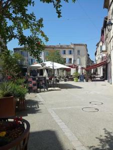 eine Stadtstraße mit Tischen, Stühlen und Gebäuden in der Unterkunft Cosy petit appartement in Gignac