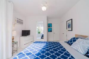 1 dormitorio con 1 cama azul y blanca y TV en BEACH VIBES, en Miami Beach