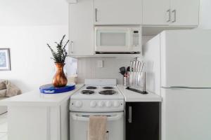 a white kitchen with a stove and a microwave at BEACH VIBES in Miami Beach