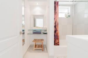 a white bathroom with a shower and a wooden stool at BEACH VIBES in Miami Beach