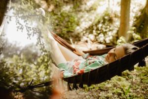 a woman laying in a hammock in the woods at Yurt in the Wood 